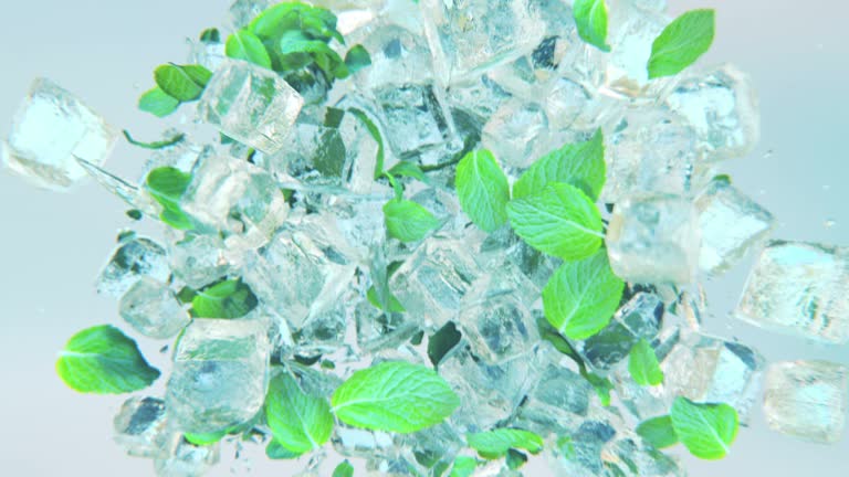 Splashing frosted ice cubes with mint leaves in 4K Slow motion