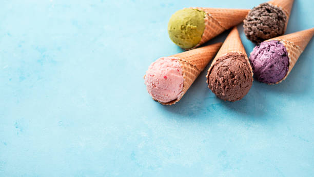 istock ice cream scoops in cones with copy space on blue 1298683624