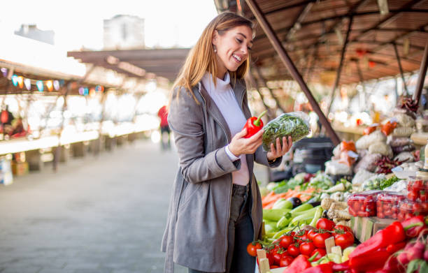 istock Young lady is at market, choosing vegetables for salad. 1298691139