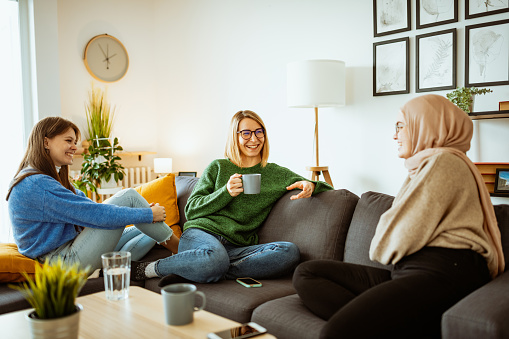 Multi ethnic group of young women having a girls' night at home after covid-19 measures are lifted and social gathering is allowed