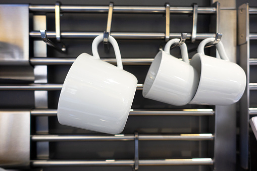 Mugs and kitchen utensils Hanging on Kitchen Wall.Modern Kitchen brass utensils, chef accessories.