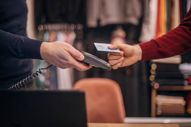 man paying with credit card in clothing store - clothing store paying cashier credit card imagens e fotografias de stock