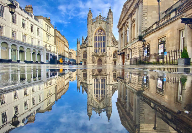 un moment de réflexion : l’abbaye de bath, en angleterre, et un centre-ville désert de bath pendant lockdown, avec une réflexion en miroir pleine largeur dans une grande flaque d’eau - bath england photos et images de collection