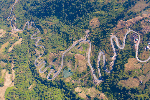 Aerial view of cars driving on curved, zigzag curve road or street on mountain hill with green natural forest trees in rural area of Phu Tub Berk, Phetchabun, Thailand.