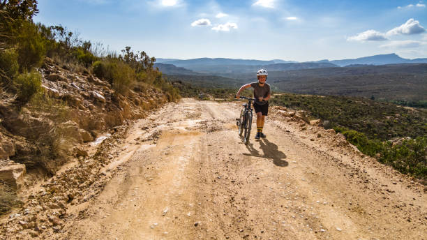 istock Boys pushing mountain bikes uphill on a dirt track mountain pass on a summers day 1298701995