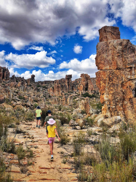 Rear view three children walking between spectacular rock formations with dramatic sky Rear view three children walking between spectacular rock formations with dramatic sky at Dwarsrivier Cederberg Mountains South Africa cederberg mountains photos stock pictures, royalty-free photos & images