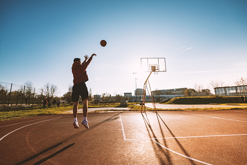 Man and woman playing basketball outdoors in winter or autumn, plenty of copy space on the image