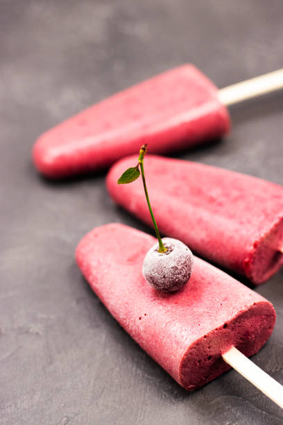 istock frozen red ice cream on a stick with a cherry in close-up on a black background 1298709268
