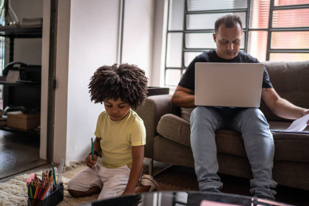 istock Father sitting on a couch working while son is playing at home 1298715329