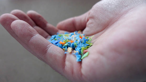 Side view of а person holding micro plastics in his hand. Non-recyclable materials. Selective focus with shallow depth of field. stock photo