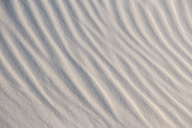 istock Natural background with patterns on the sand of dune. Background, sand, light, beige, wave, reflect, shadow, summer. Beautiful sand`s background with graphics waves, shadows and lights. 1298730832