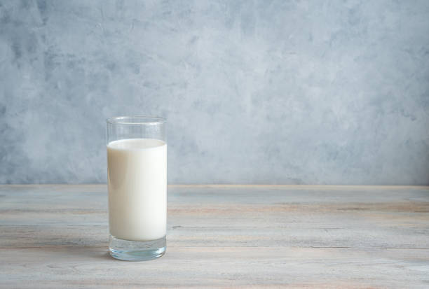 istock Milk in a long transparent glass on a gray-blue background. Side view with copy space 1298731700
