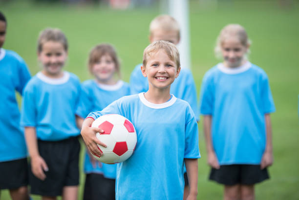istock Boy holding soccer ball at the field 1298736031