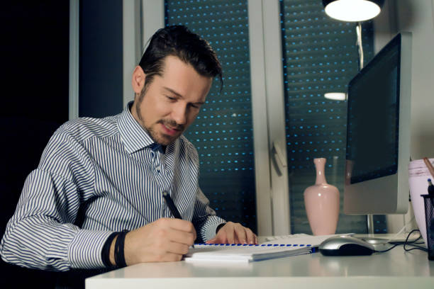 istock Mid adult businessman going through paperwork while working late at home. 1298738825