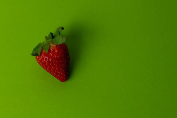 istock Single strawberry on bright green background 1298739719