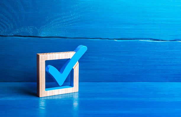A wooden frame with a blue checkmark symbol is positioned on a blue wooden surface, set against a textured blue background.