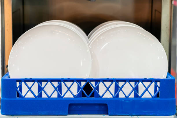 Many white plate or dishes arranged in a basket  after cleaning from dishwasher machine