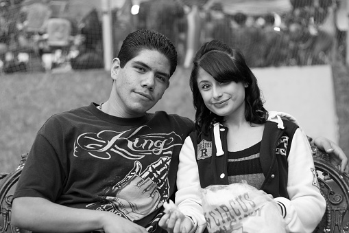 Santa Fe, NM: A young Latinx couple sitting on a bench on the historic Santa Fe Plaza on a summer evening.