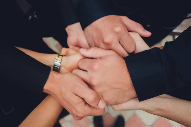 istock two man and three women holding hands on a table implying a polyamory relationship or love triangle. 1298757656