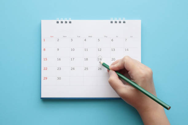 Hand with pencil mark on calendar date Hand with pencil mark on calendar date on blue background calendar photos stock pictures, royalty-free photos & images