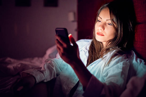 kvinna är textning i sängen på natten - kvinna telefonbedragare bildbanksfoton och bilder