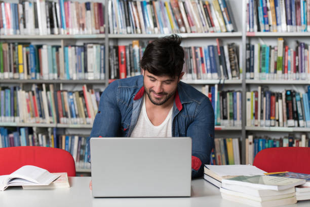 istock Male Student Typing on Laptop in the University Library 1298759600