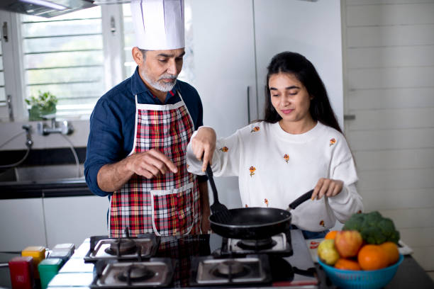 istock Father giving culinary lessons to daughter at kitchen 1298770307