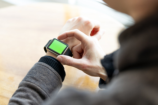 Close-up of woman wearing chroma key green screen smart watch in office or home.