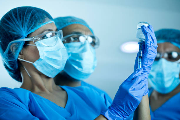Doctors team preparing injection with covid-19 vaccine Doctors team with vial of covid-19 virus vaccine and syringe antiviral drug stock pictures, royalty-free photos & images