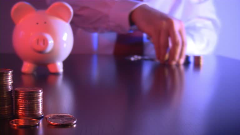 Businessman counting coins from a pile of change. Piggy bank.