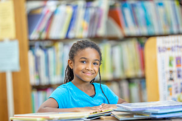 istock Smiling school girl at the school library 1298780497