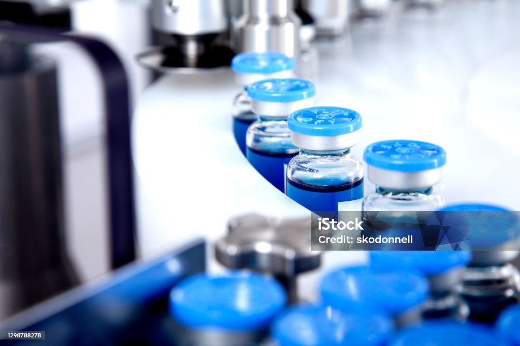 Glass bottles in production in the tray of an automatic liquid dispenser, a line for filling medicines against bacteria and viruses, antibiotics and vaccines Medicine Stock Photo