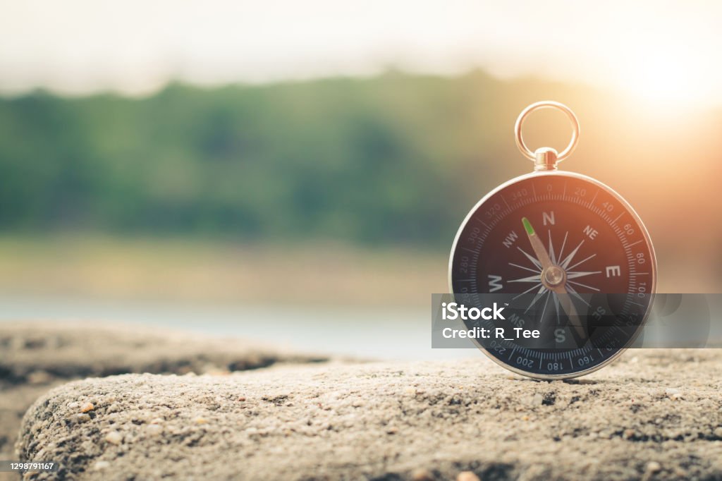 Compass of tourists on mountain at sunset sky. Navigational Compass Stock Photo