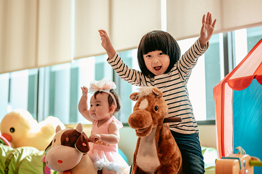 Two children were having fun playing rocking horses together.Family with children at home. Love, trust and tenderness.Happy family lifestyle concept.