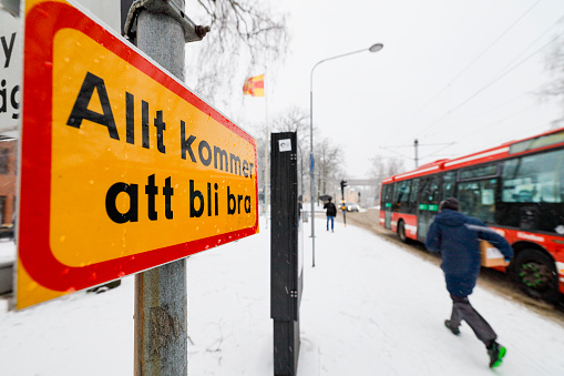 Stockholm, Sweden Jan 26, 2021 A street sign, pedestrian and a bus in front of a church in Grondal in the snow. TRANSLATION: \