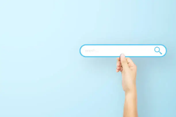 Photo of Hand holding paper with search bar on light blue background. Concept of searching information data on internet networking