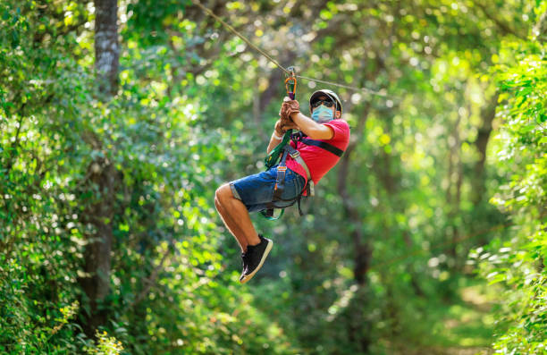 Boy teenager on a zip line in Costa Rica wearing protective mask Boy teenager on a zip line in Costa Rica wearing protective mask canopy tour photos stock pictures, royalty-free photos & images