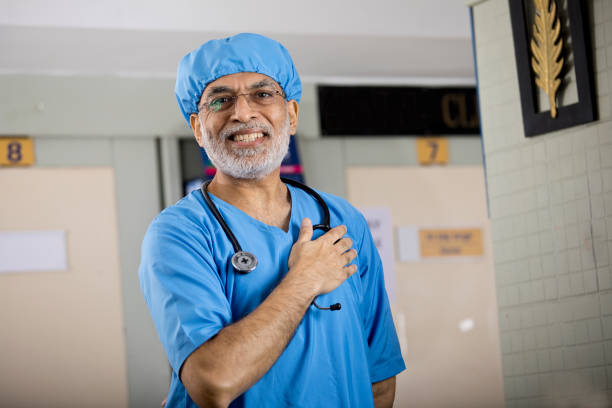 Happy male surgeon with hand on chest Confident male surgeon with hands on chest at hospital man-hand-on-chest stock pictures, royalty-free photos & images