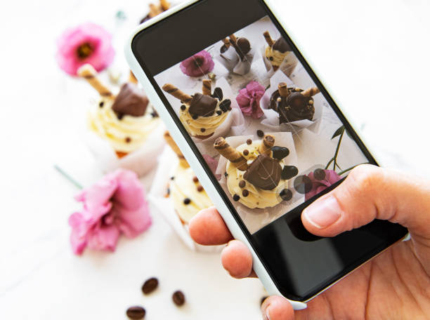 девушка делает фото кексов на смартфоне - десерт фотографии стоковые фото и изображения