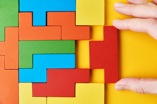 istock Logical thinking and finishing task concept. Woman hand adding last missing wooden block to finish puzzle 1298809897