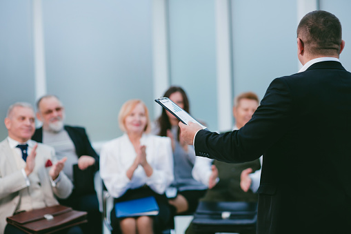 A senior businesswoman holding a speech for an audience in the conference room of a hotel