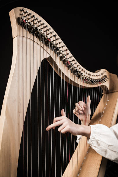 istock Hands playing wooden harp on black background 1298820611