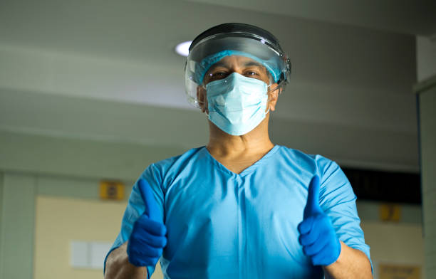 Doctor with protective mask and a face shield giving thumbs up Confident doctor with a protective mask and a face shield giving thumbs up gesture india hospital stock pictures, royalty-free photos & images