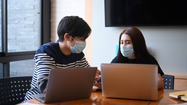 istock Two young creative designer in protective masks works together in the office. 1298823002