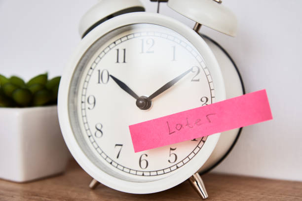 istock Procrastination and delay concept. Sticky note with word later on white alarm clock. Urgency time 1298824019