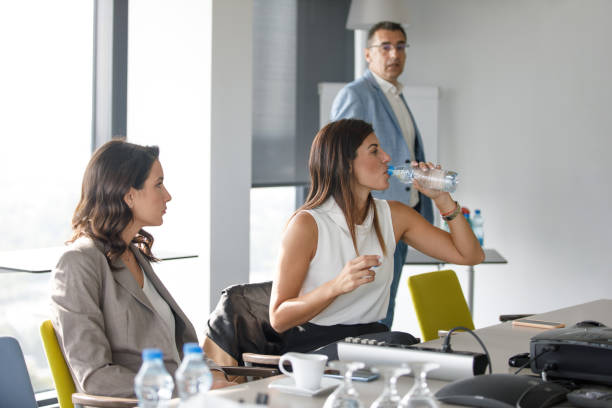 empresaria bebiendo agua de botella en una reunión en la mesa de conferencias - office water business meeting fotografías e imágenes de stock