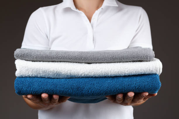 istock A woman is holding a stack of clean rolled towels. 1298825088
