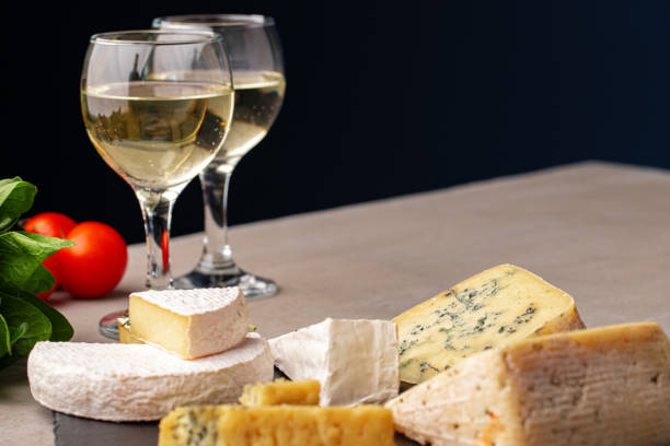 Different types of cheese and wine served on gray table
