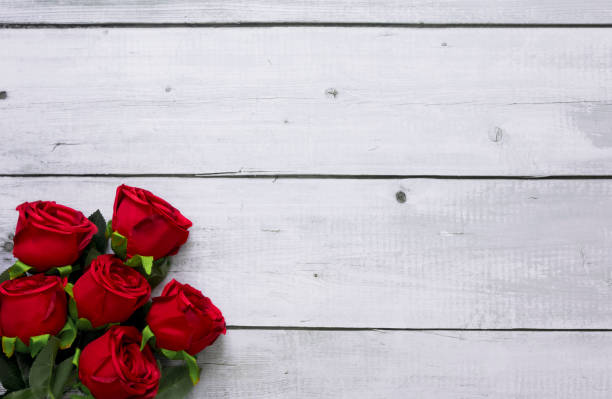 istock Red roses on white wooden desk with copy space 1298830425