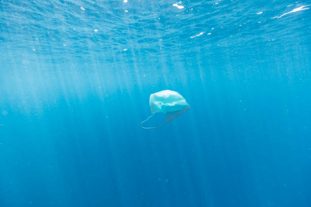 istock Face mask pollution in the clear blue pacific ocean 1298833856